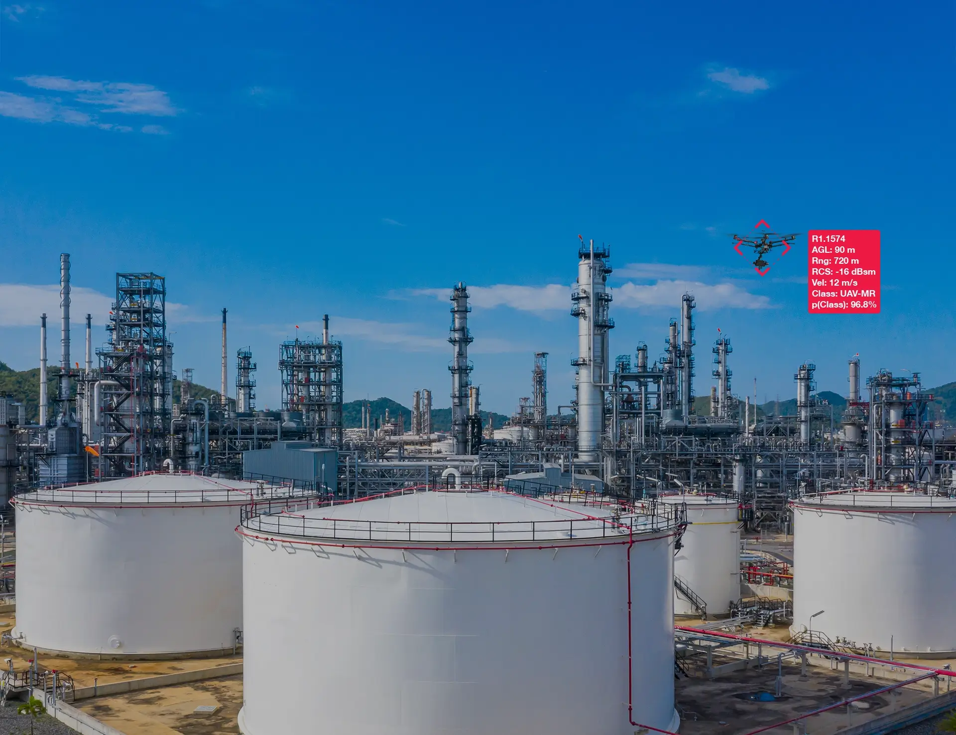 Drone flying over oil refinery tanks and equipment under a clear blue sky with data overlay.