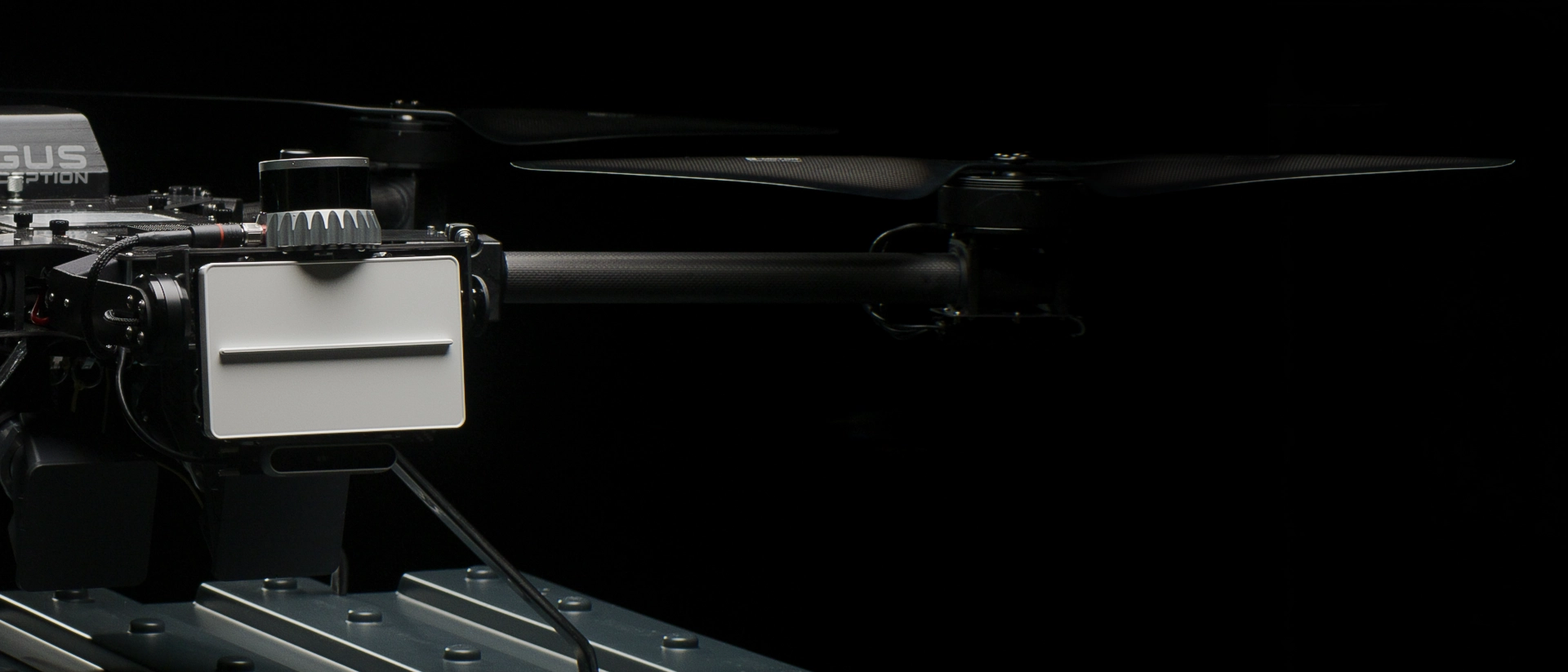 Close-up of drone arm with propeller and sensor device on a black background.