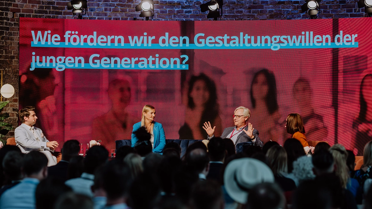 Eine Gruppe von Menschen sitzt vor einem großen Bildschirm.
