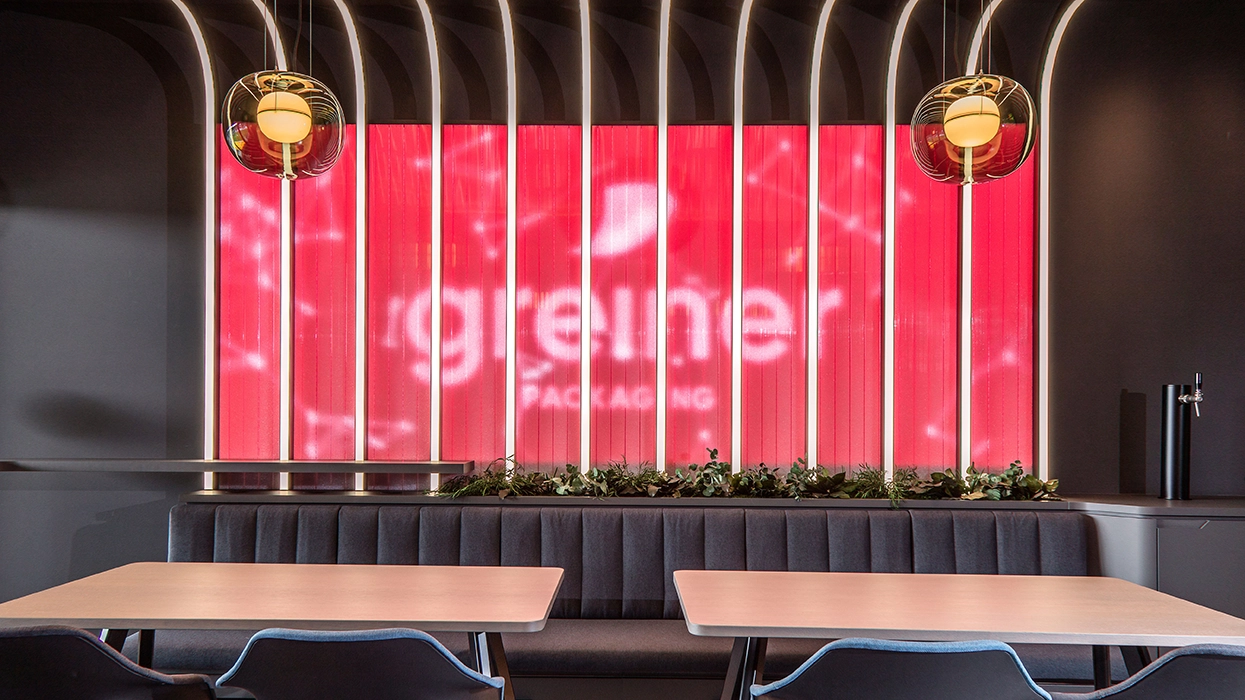 Ein Restaurant mit Tischen und Stühlen vor einer großen Leinwand.