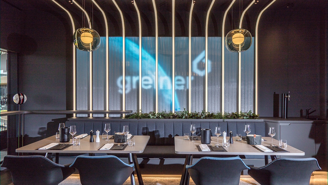 Ein Restaurant mit Tischen und Stühlen und einer Projektionsfläche.
