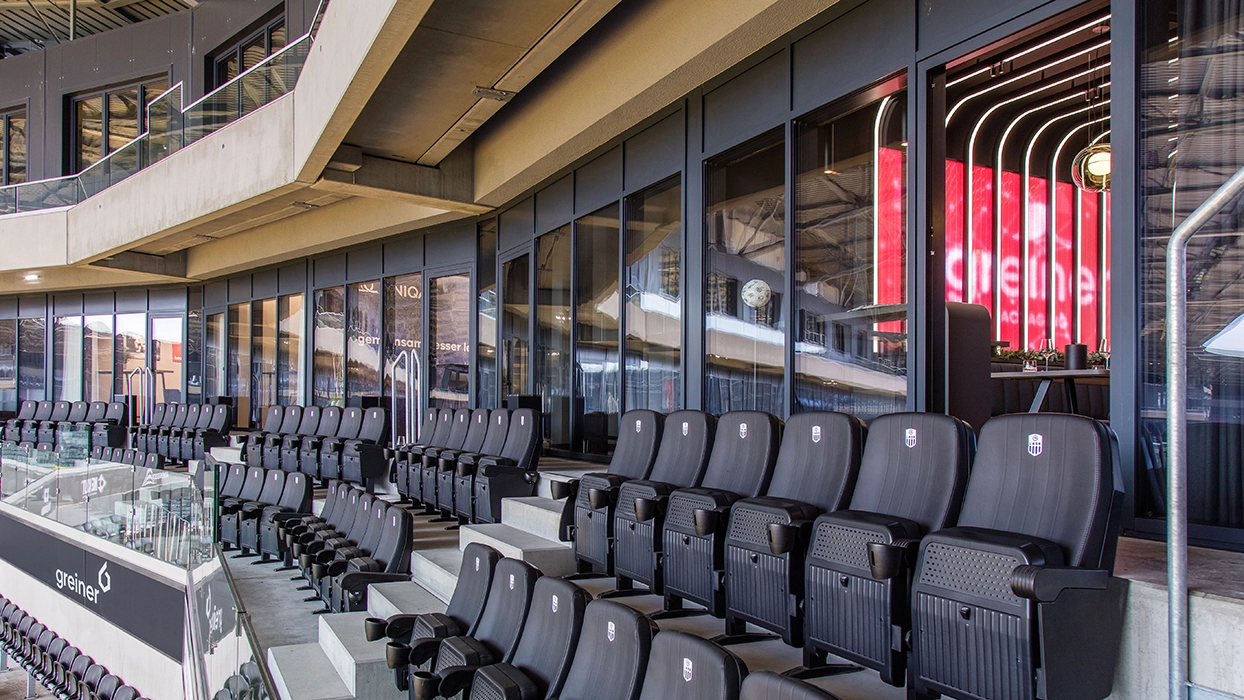 Ein Stadion mit Sitzreihen und einer Glaswand.