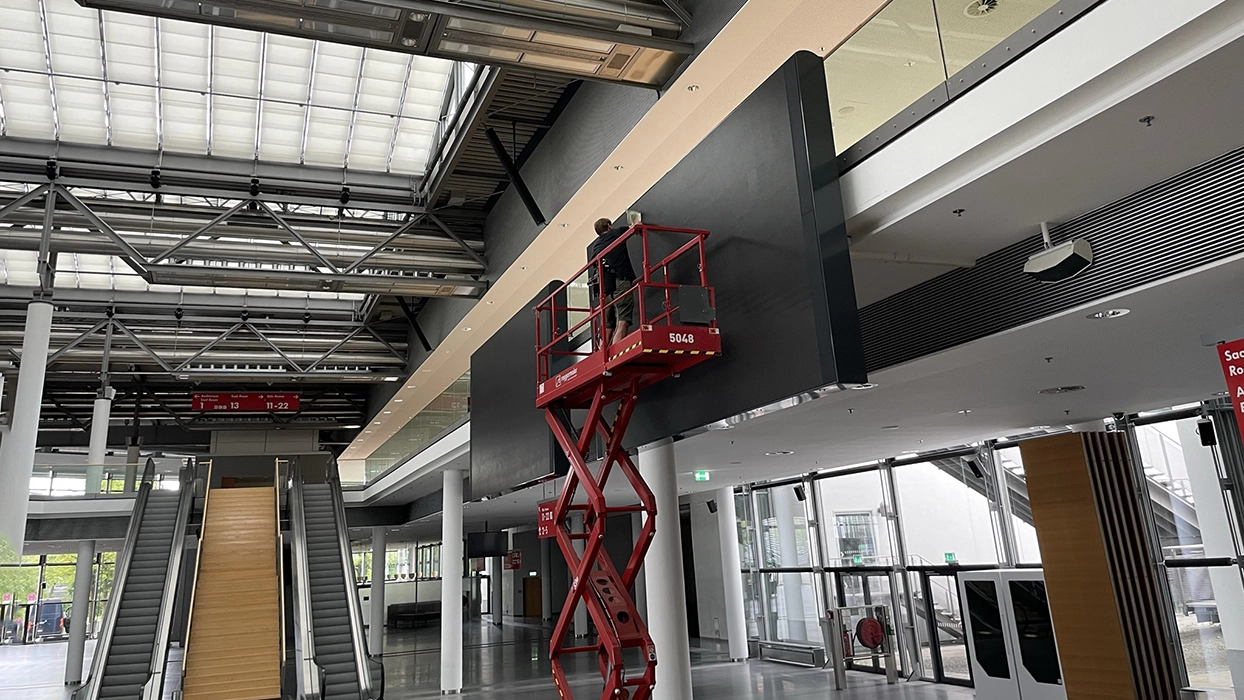 Ein Mann arbeitet an einem Aufzug in einem großen Gebäude.
