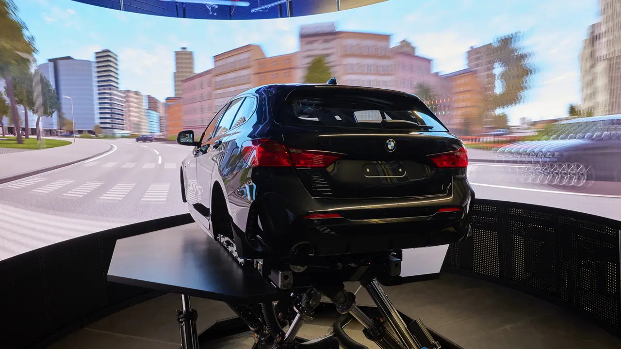 BMW driving simulator in front of a curved LED wall showing a virtual road scene.