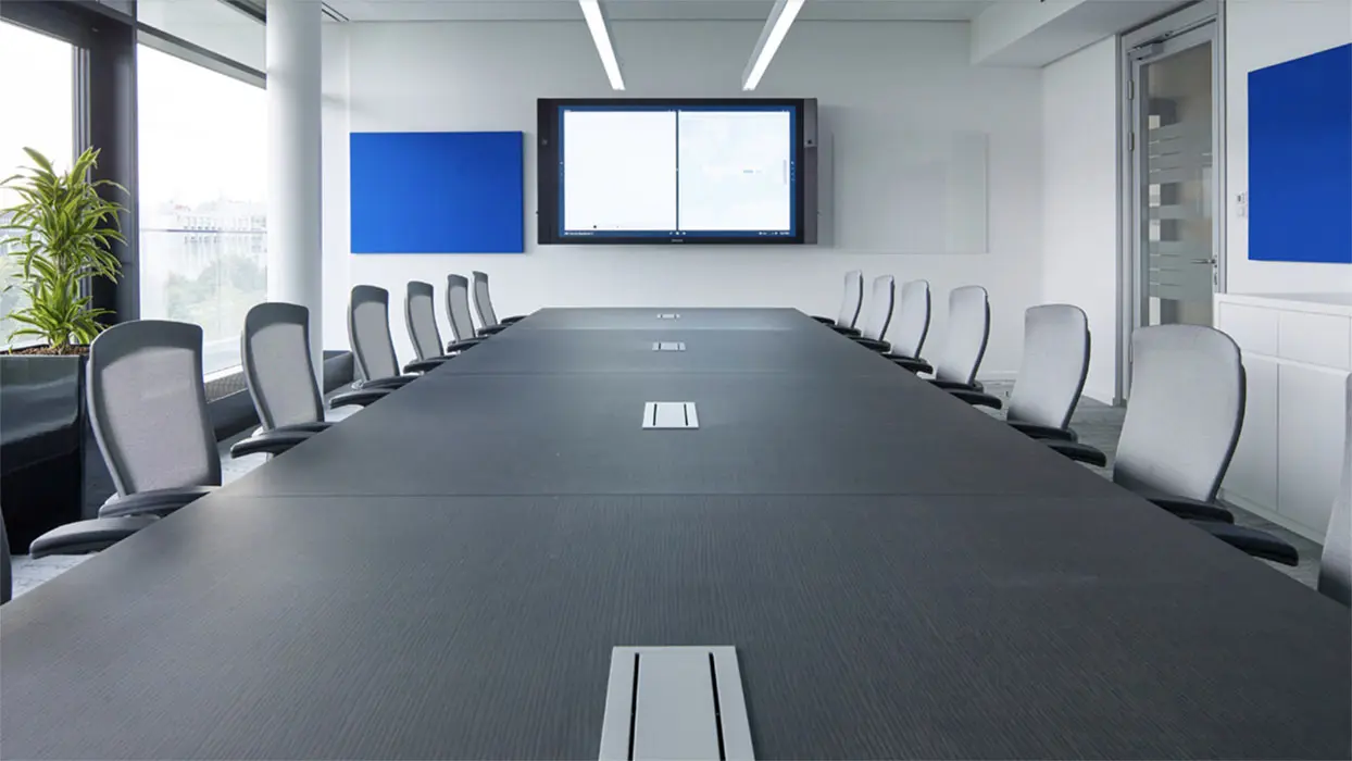 Meeting room at Microsoft with a long conference table and two wall-mounted displays.