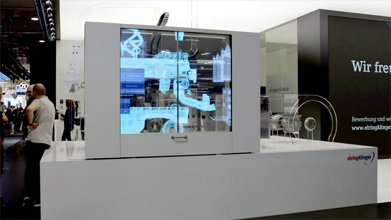Transparent display in front of vehicle components on the ElringKlinger exhibition stand.