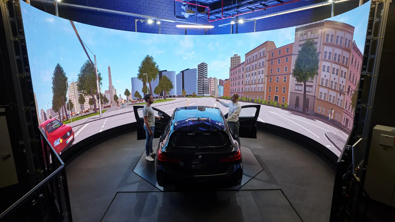 BMW vehicle in front of a curved LED surface showing a virtual road scene in a driving simulator.