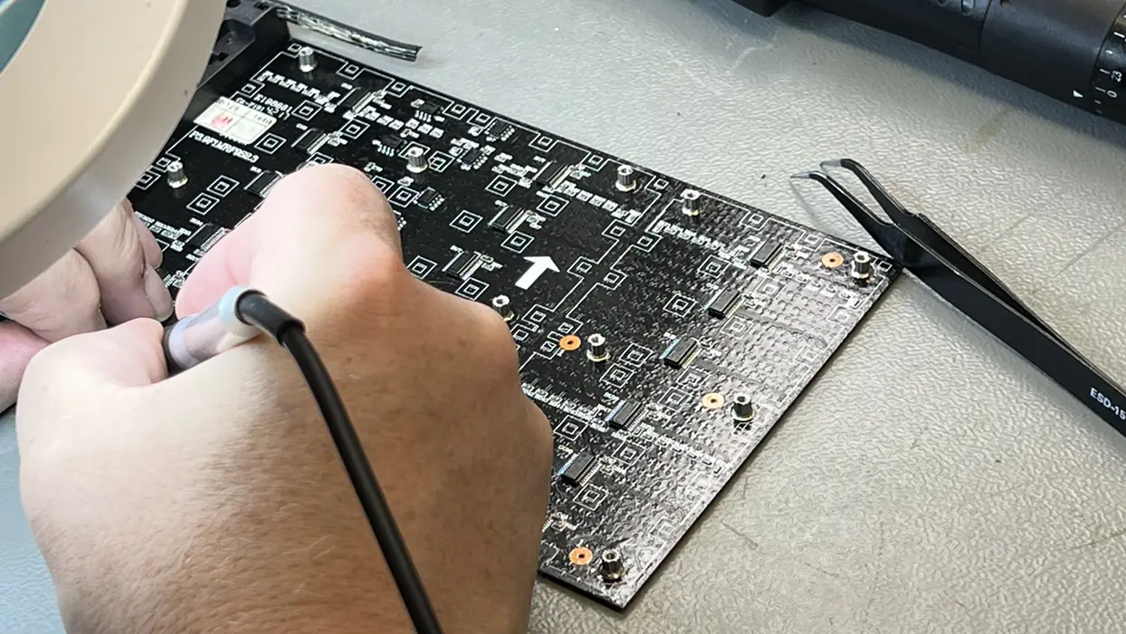 Work on an electronic circuit board with a soldering iron.