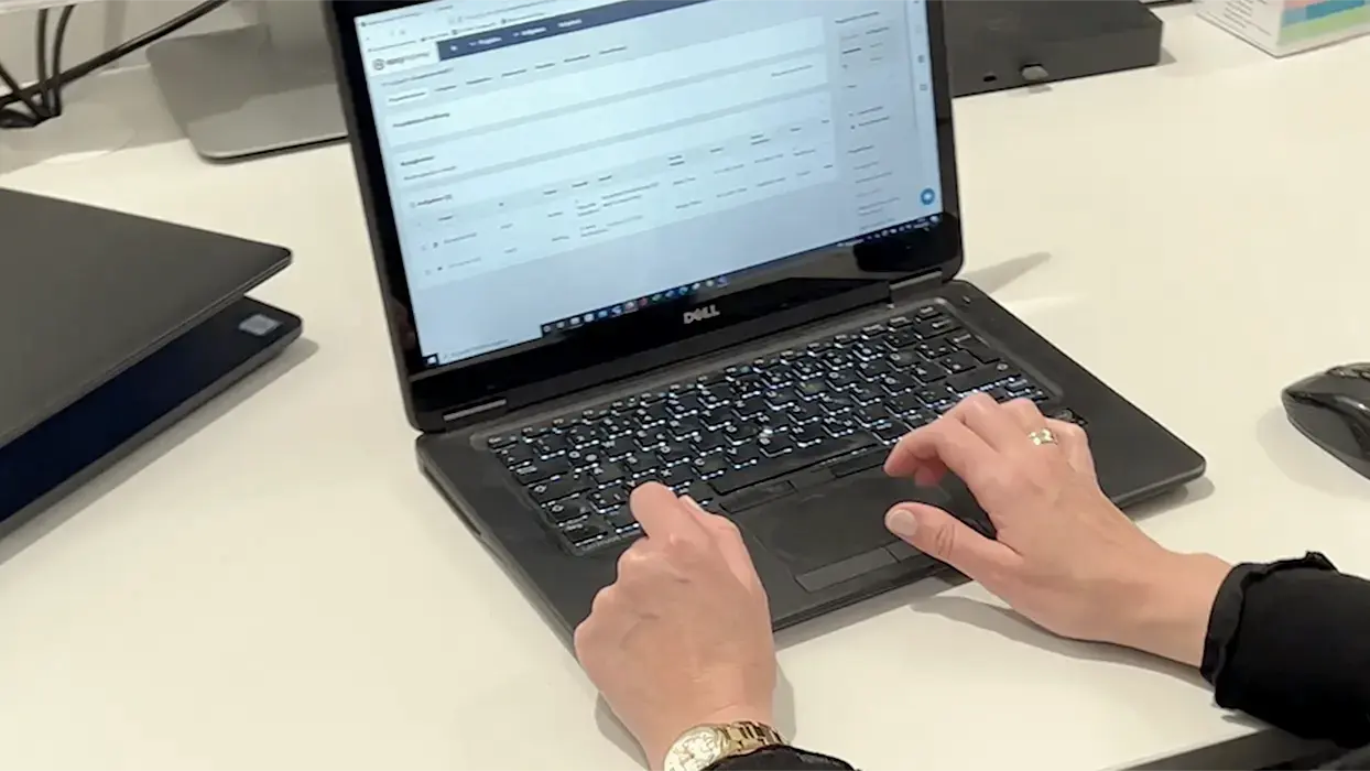 Hands at a laptop with a ticketing system open on a desk.