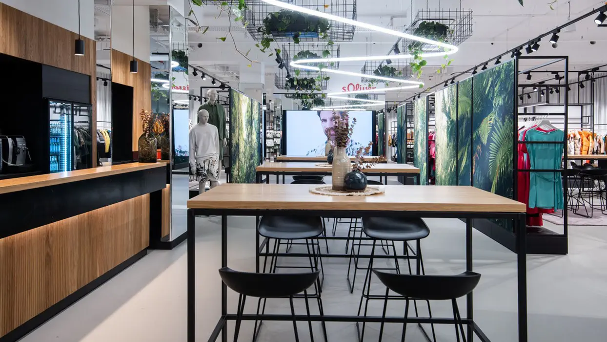 Showroom with meeting tables, fashion displays and large digital screens.