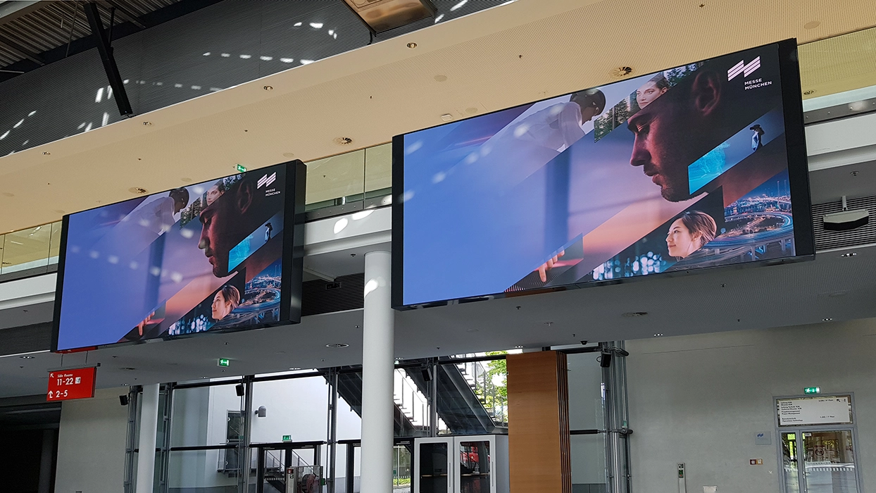 Two large television screens hanging inside a building.