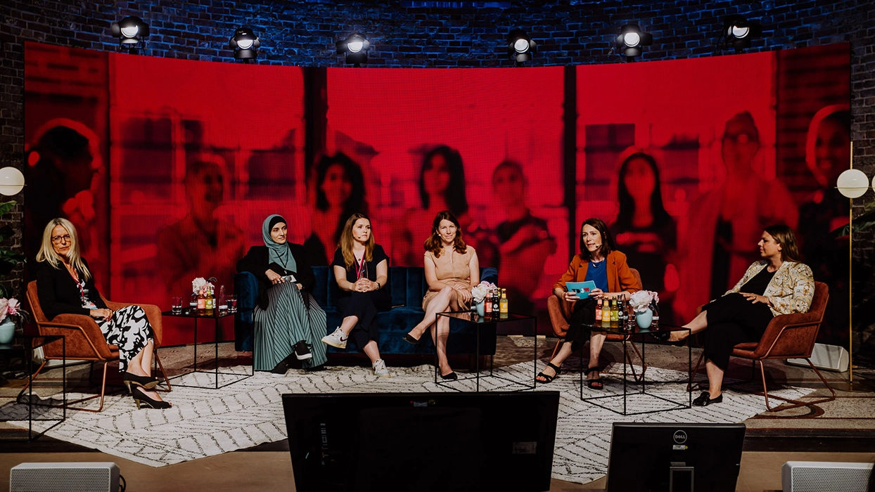 A group of women seated in front of a red screen