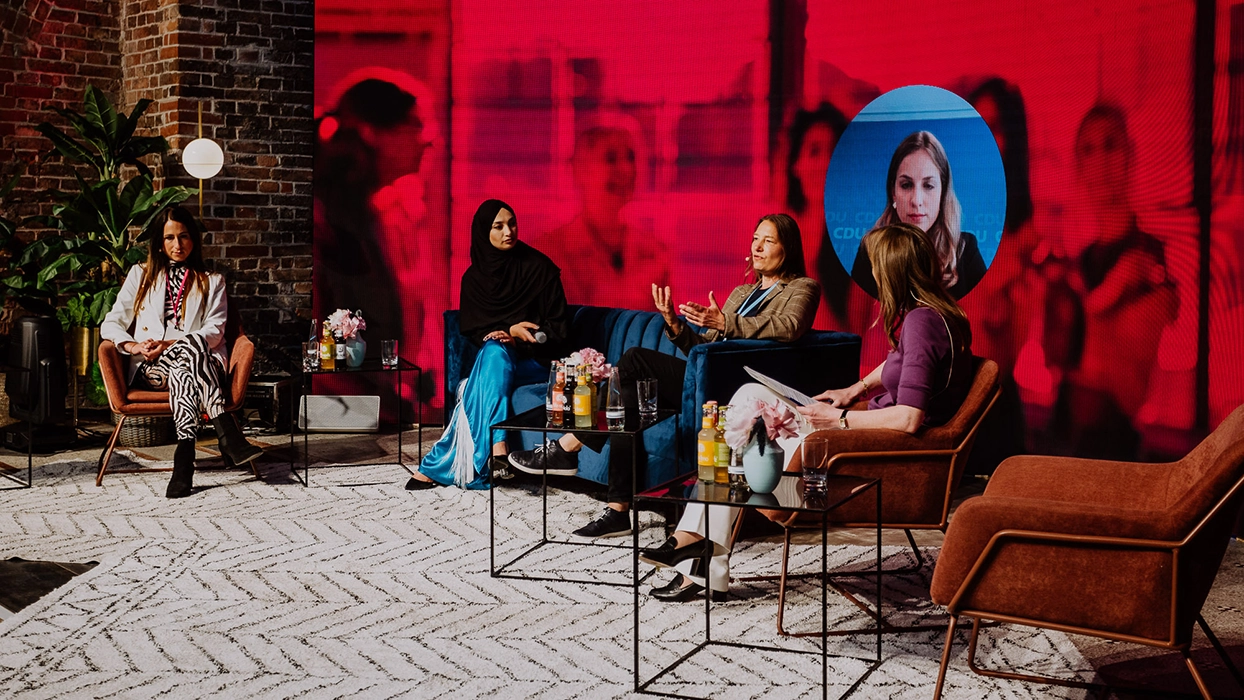 Women seated in front of a red wall