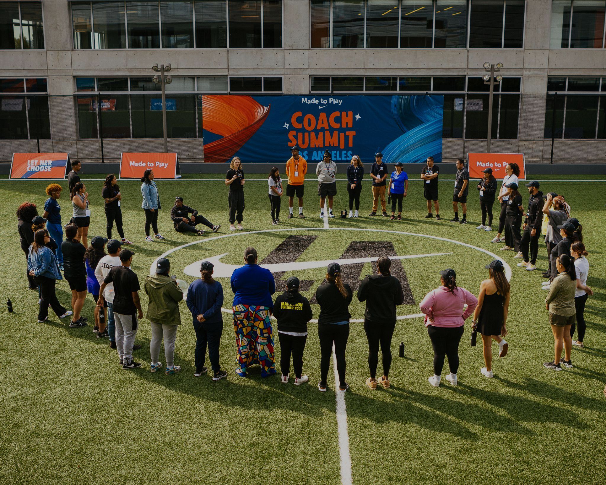 Coaches circled on a turf field at Nike's Made to Play Coach Summit in Los Angeles