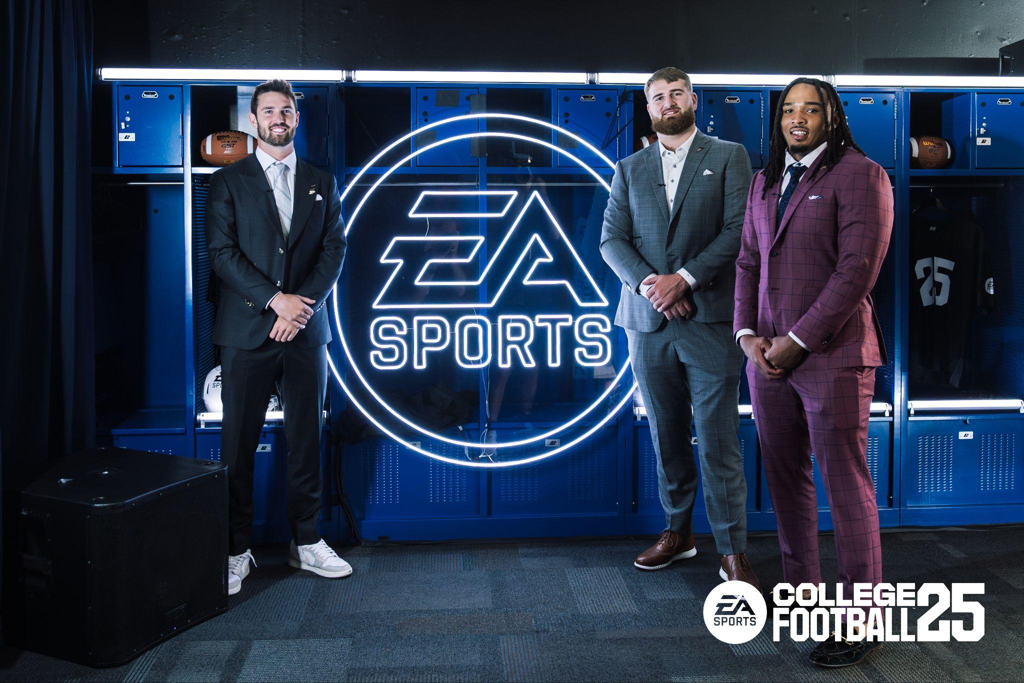 Three college players in suits in front of a neon EA Sports sign in a locker room set