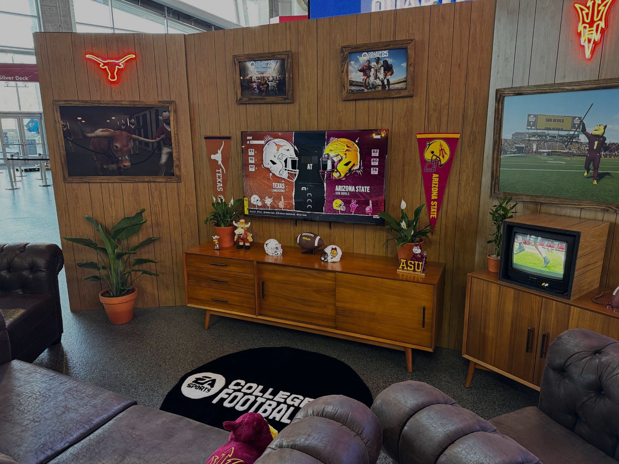 College Football 25 game room styled with school pennants, a retro TV and leather couches