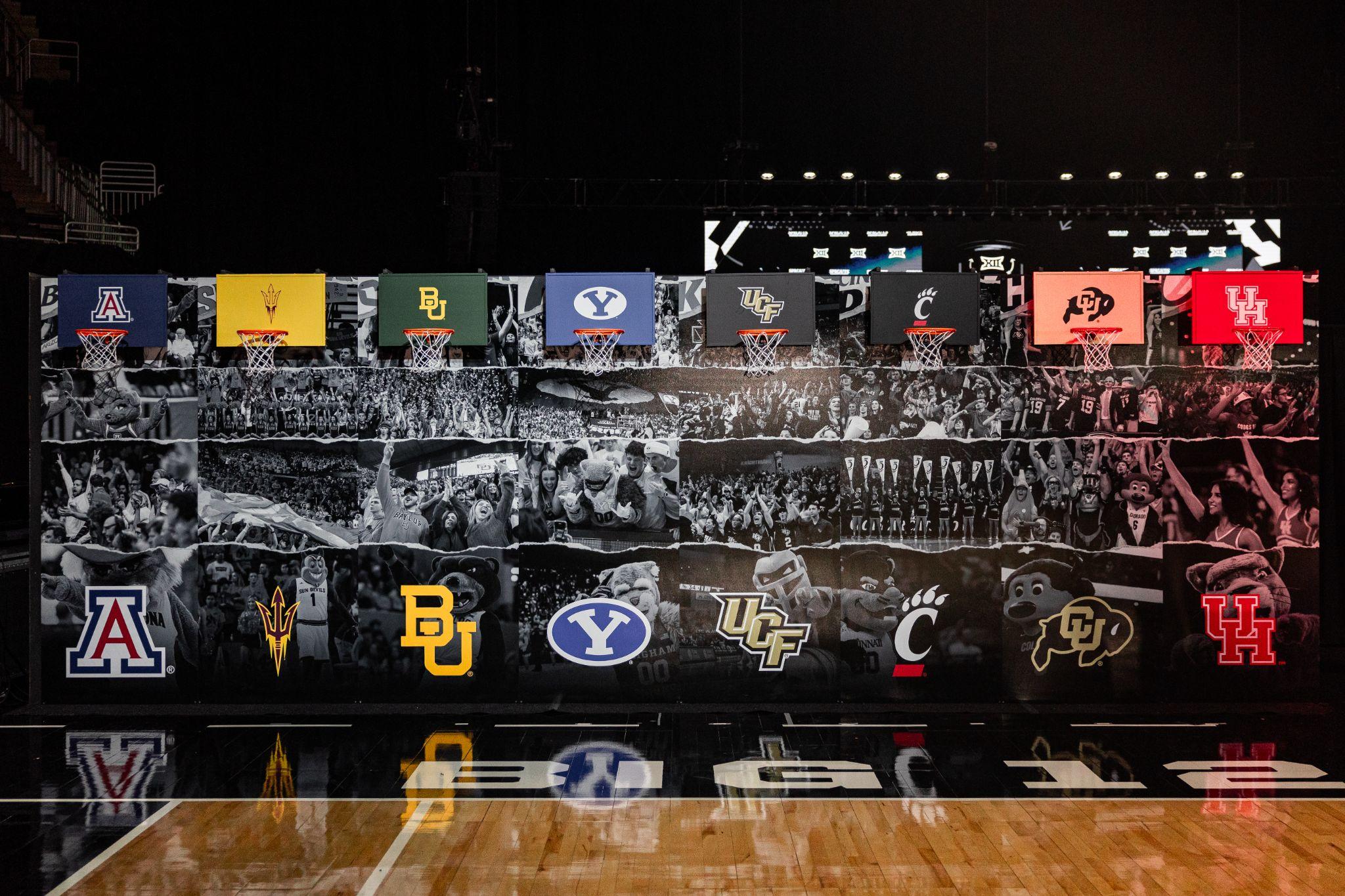 Big 12 media day backdrop with a row of team-branded basketball hoops above a crowd mural
