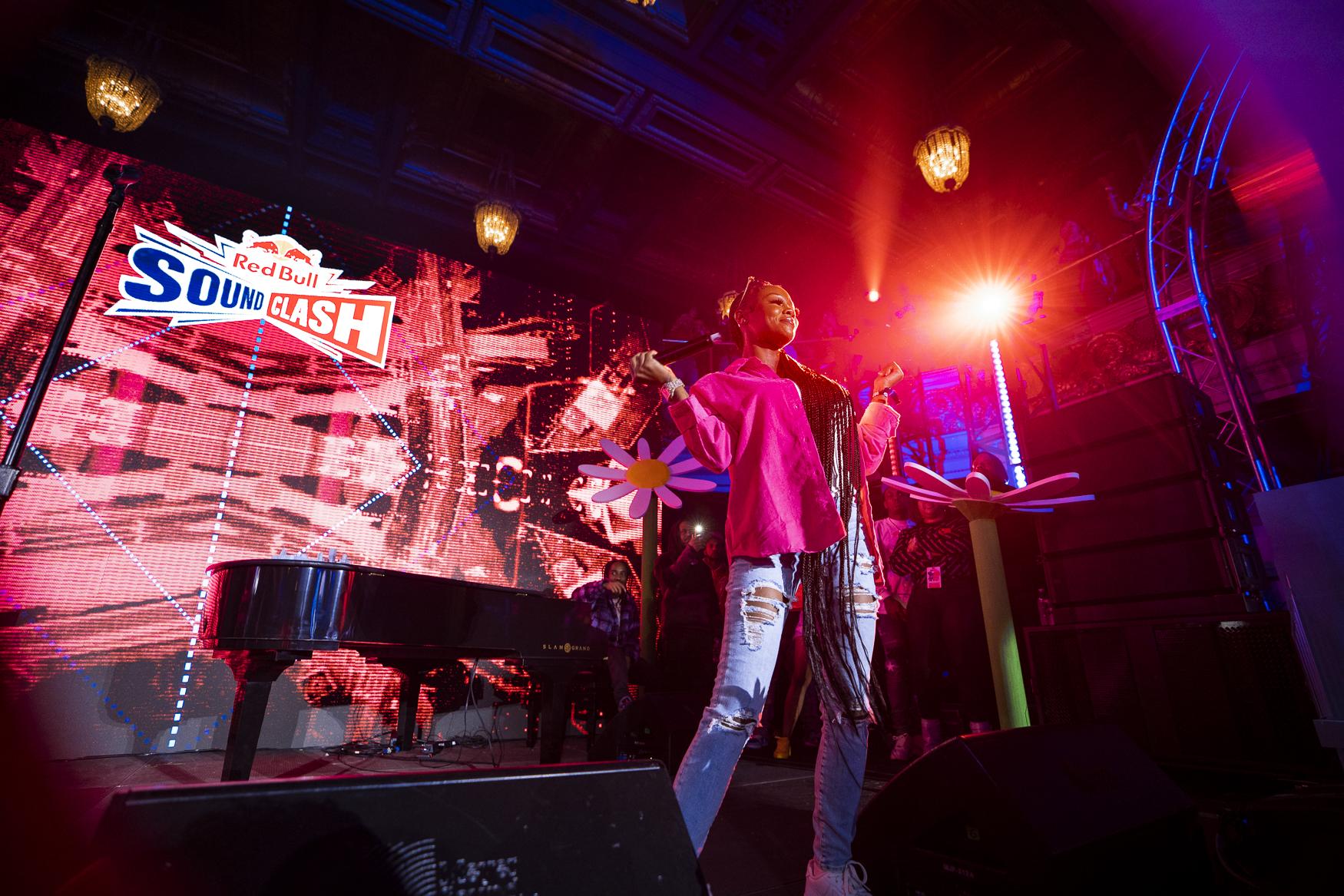 Performer on stage beside a piano under Red Bull Soundclash signage