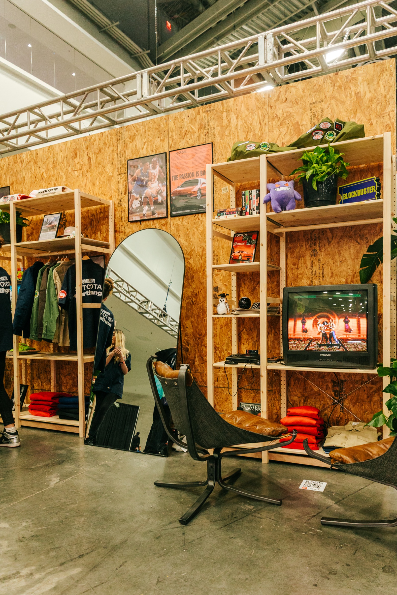 Plywood garage set with shelving, a lounge chair and framed posters in the Toyota booth