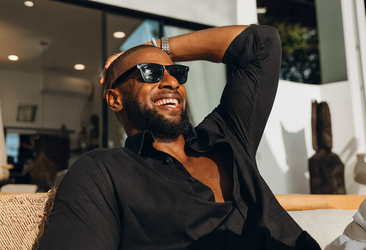 Man in a black shirt and sunglasses smiling indoors