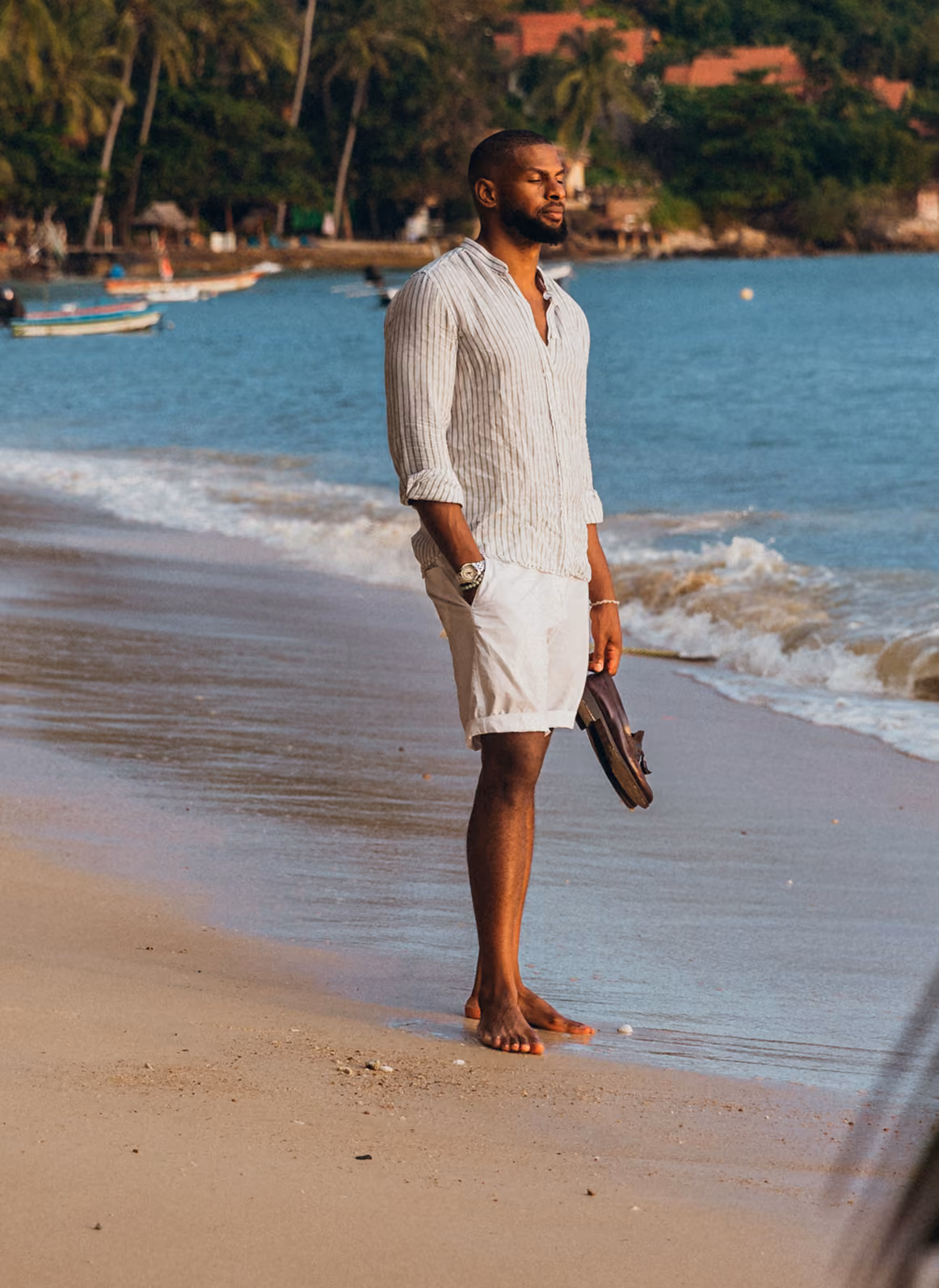 Man standing on a beach at sunset looking out at the water