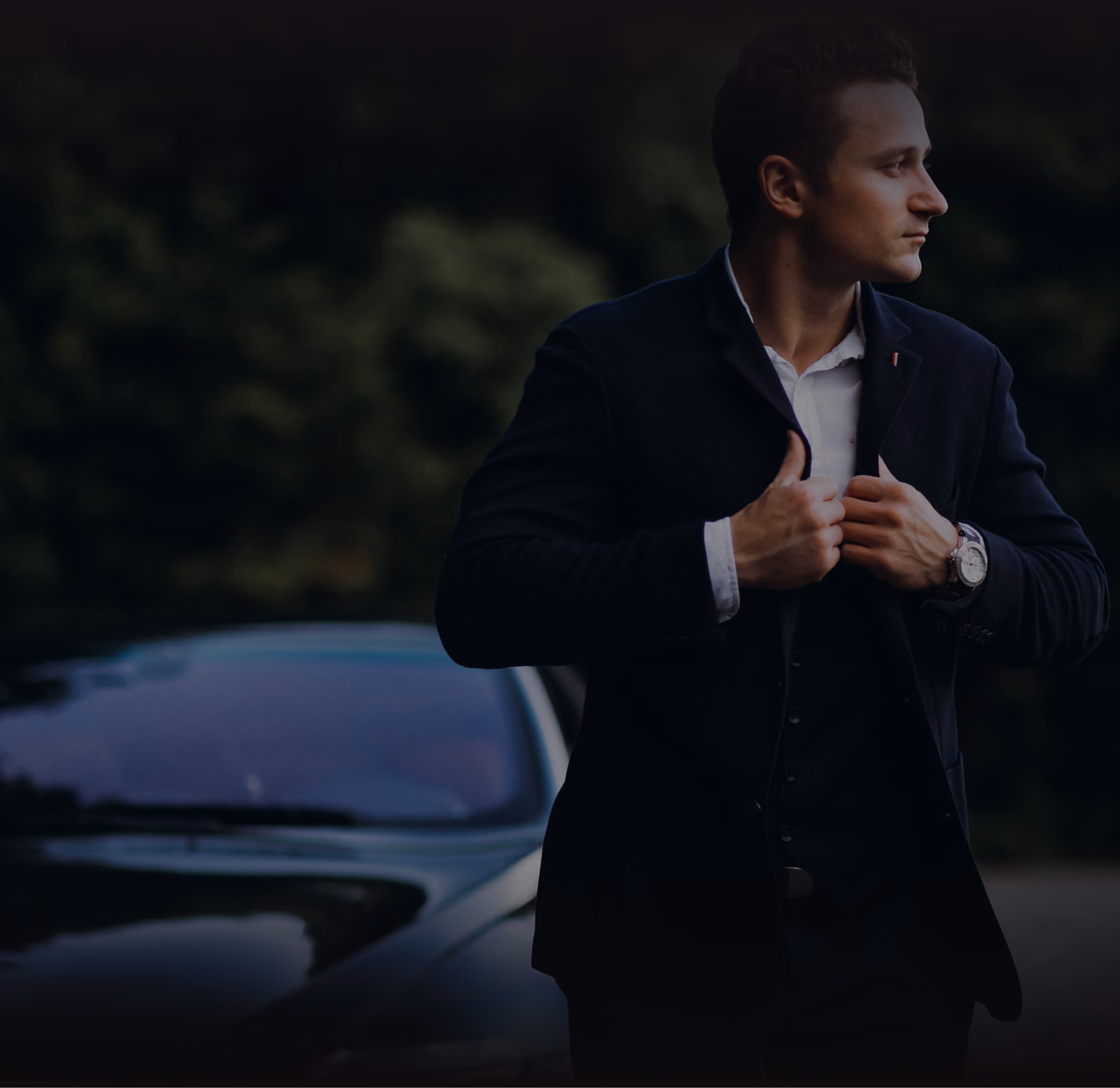 Man in a navy blazer adjusting his jacket, photographed outdoors