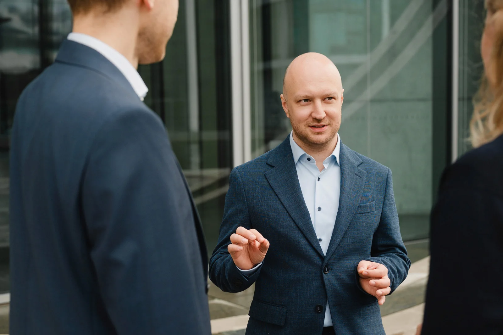 Dr. Norman Koschmieder im Gespräch mit zwei Personen vor einem Bürogebäude