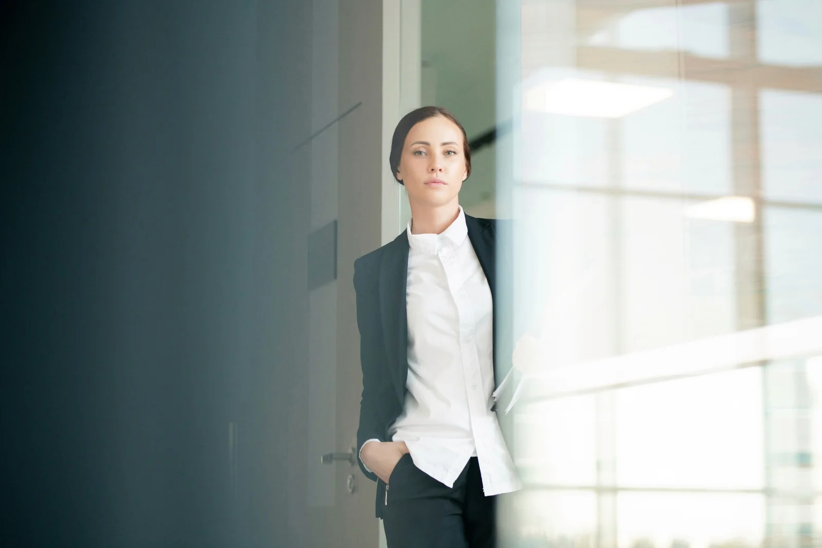 Frau im Business-Outfit an der Glastür eines Bürogebäudes