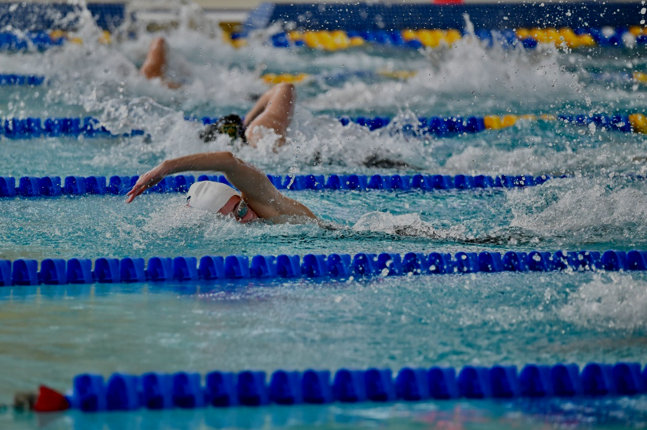 Student swimmer racing freestyle in a pool lane