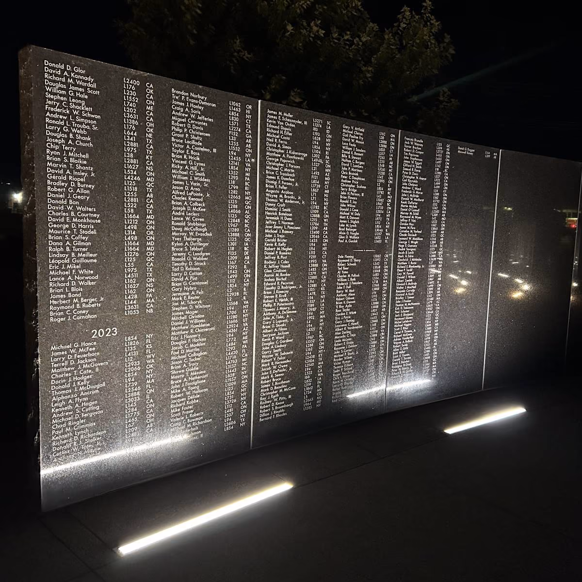 Memorial wall of names illuminated at night