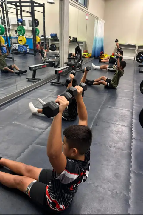 Young athlete performing a dumbbell strength exercise during a training session at ATHLTX Sports Performance in Waipahu, HI.