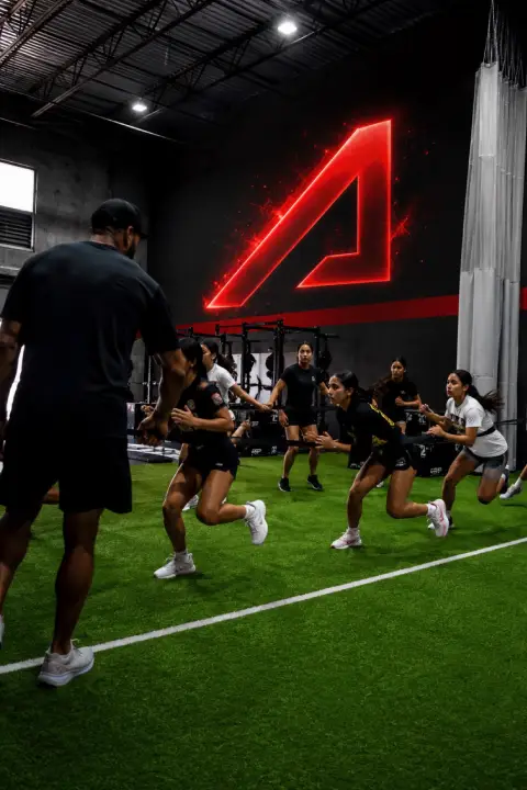 Athletes performing sprint drills on indoor turf during a group training session at ATHLTX Sports Performance in Waipahu, HI.