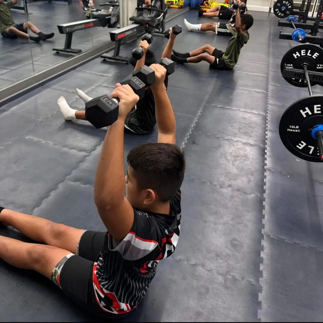 Young athlete performing a dumbbell strength exercise during a training session at ATHLTX Sports Performance in Waipahu, HI.