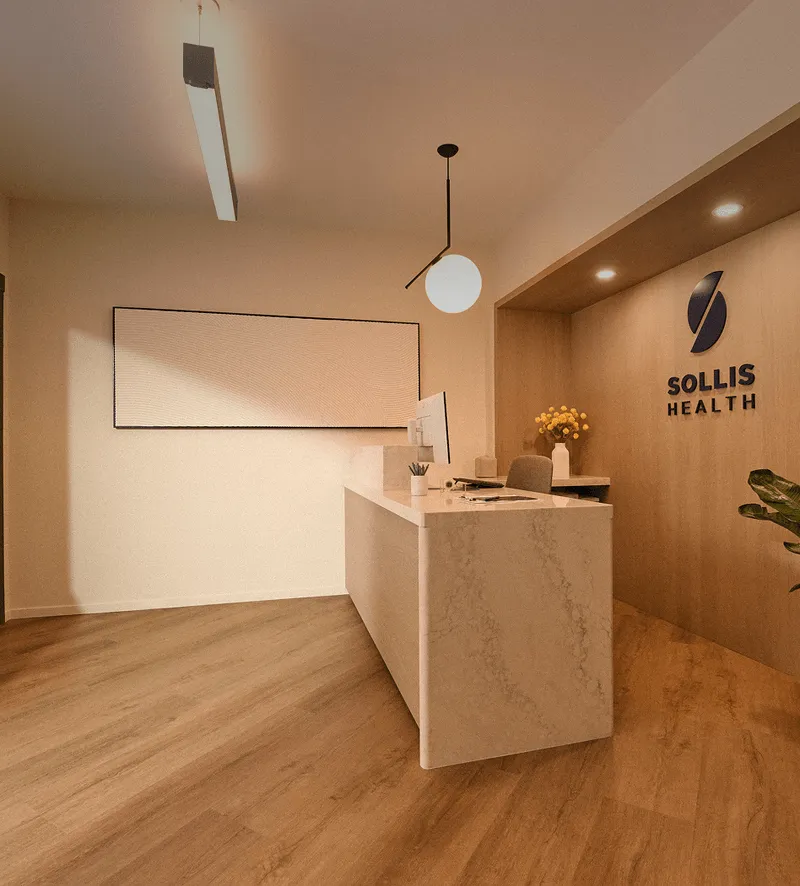 Modern medical clinic reception area with marble front desk and Sollis Health logo on wood wall.