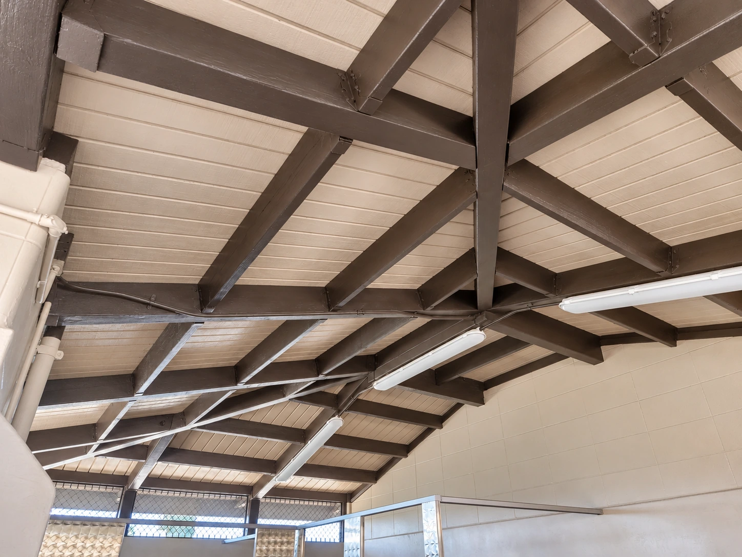 Painted exposed roof framing and LED light fixtures inside the Northwest Park restroom.