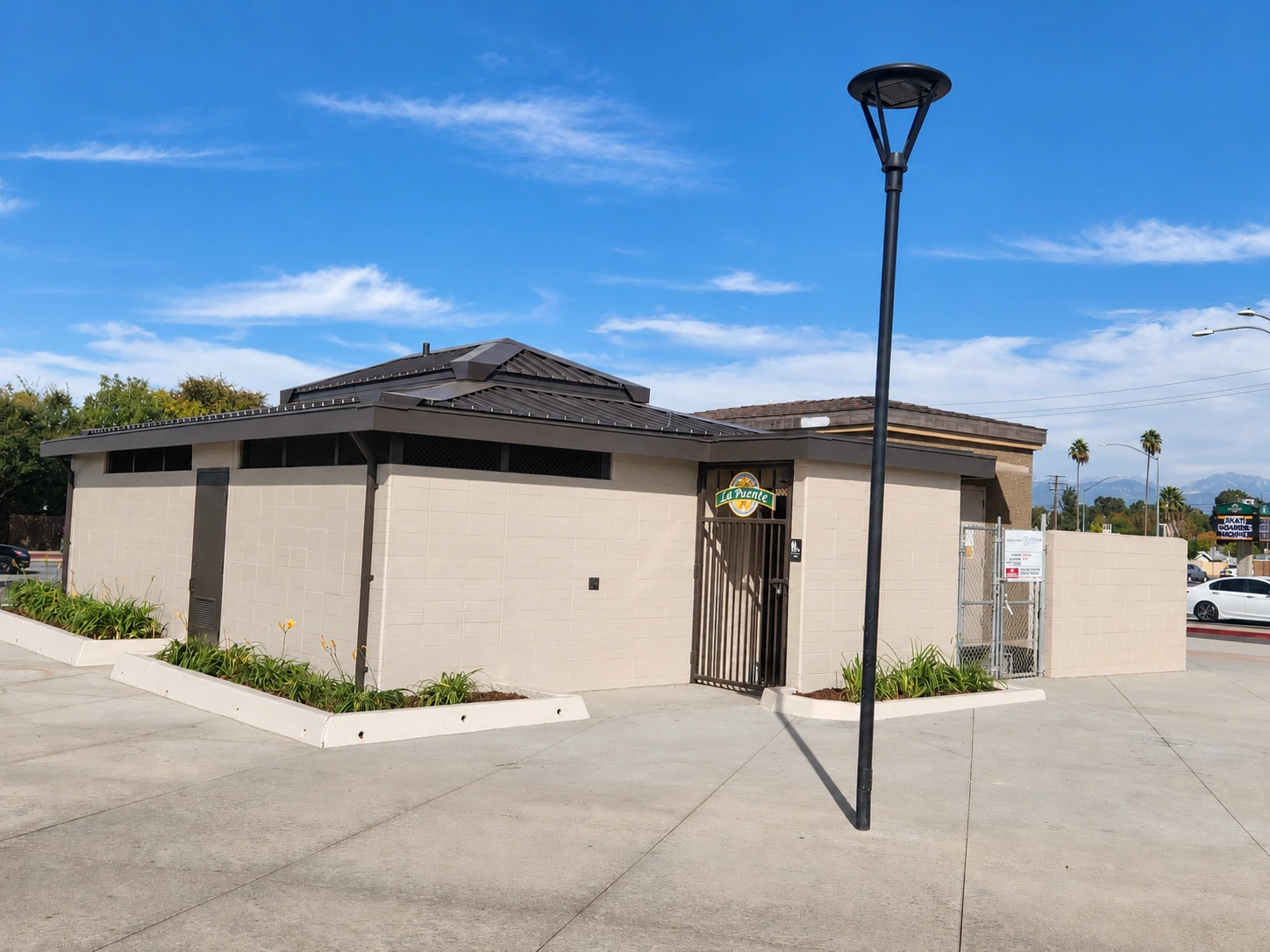 Alternate exterior view of the completed Northwest Park restroom, showing the roof, masonry walls, entry gate, and surrounding paving.