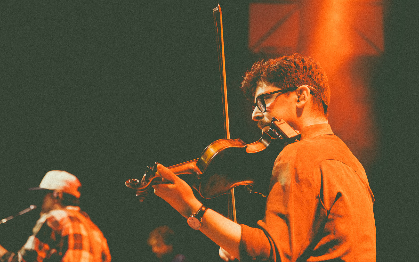 Justin Doucet du groupe Beauxmont jouant du violon sous un éclairage orangé.
