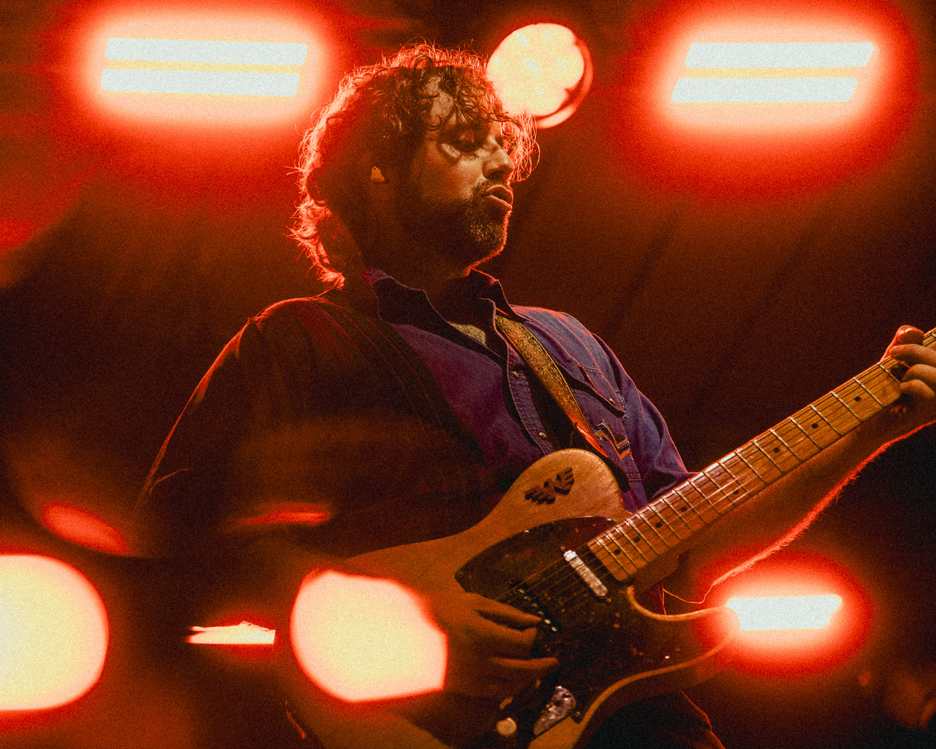 Patrick Dugas du groupe Beauxmont jouant de la guitare électrique sous un éclairage de scène rouge.