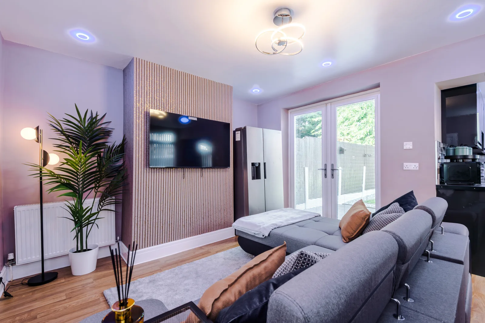 Living room with a large corner sofa, wall-mounted TV and French doors to the garden at 3 Albert Gardens