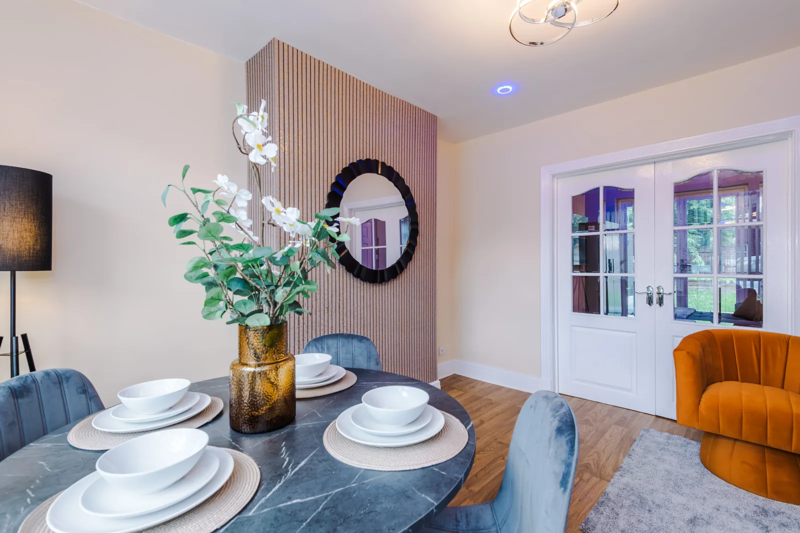 Dining room with a round table laid for four and a slatted feature wall at 3 Albert Gardens