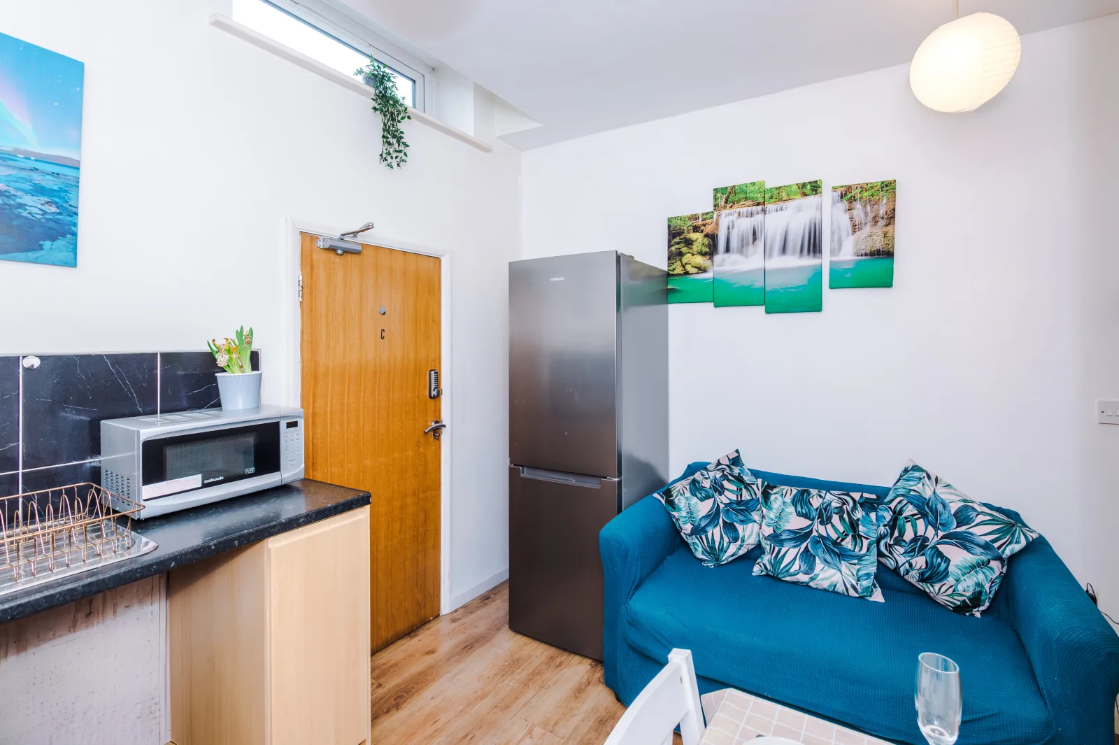 Living area with a teal sofa and fridge freezer at Flat 5, Pendleton Way