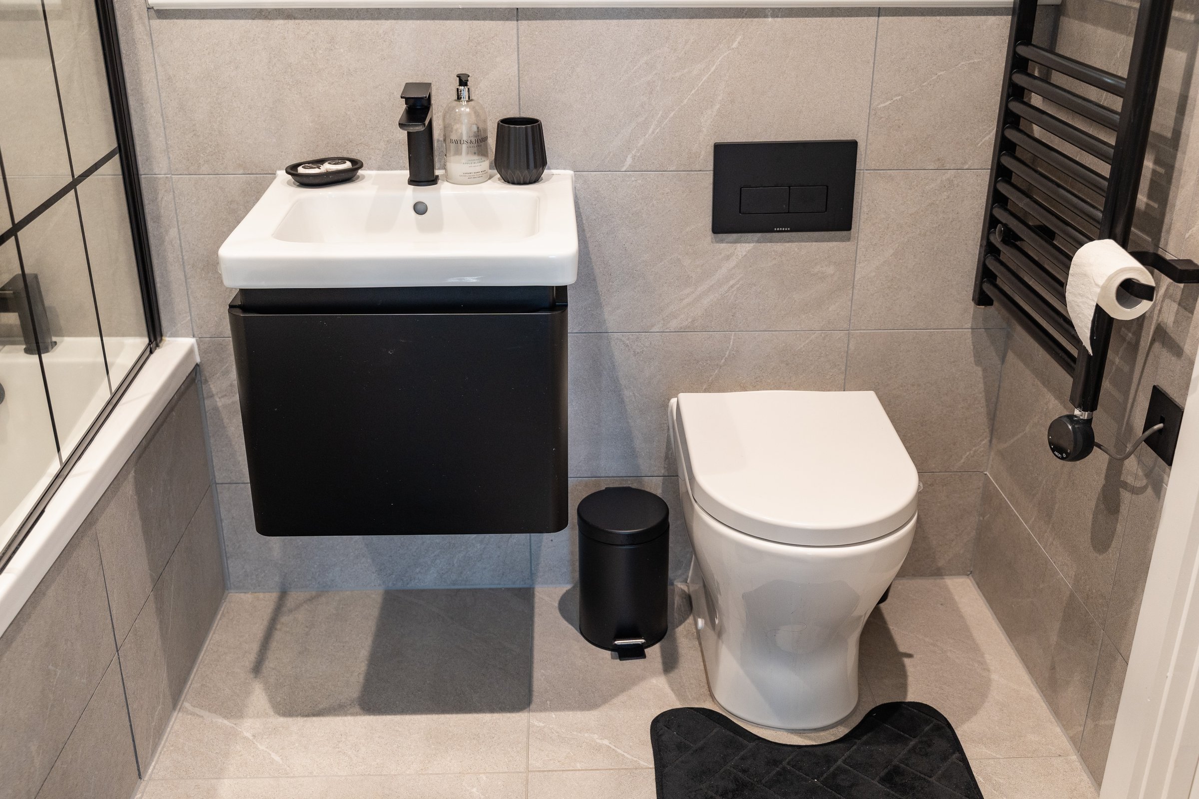 Bathroom with a wall-mounted basin, toilet and heated towel rail