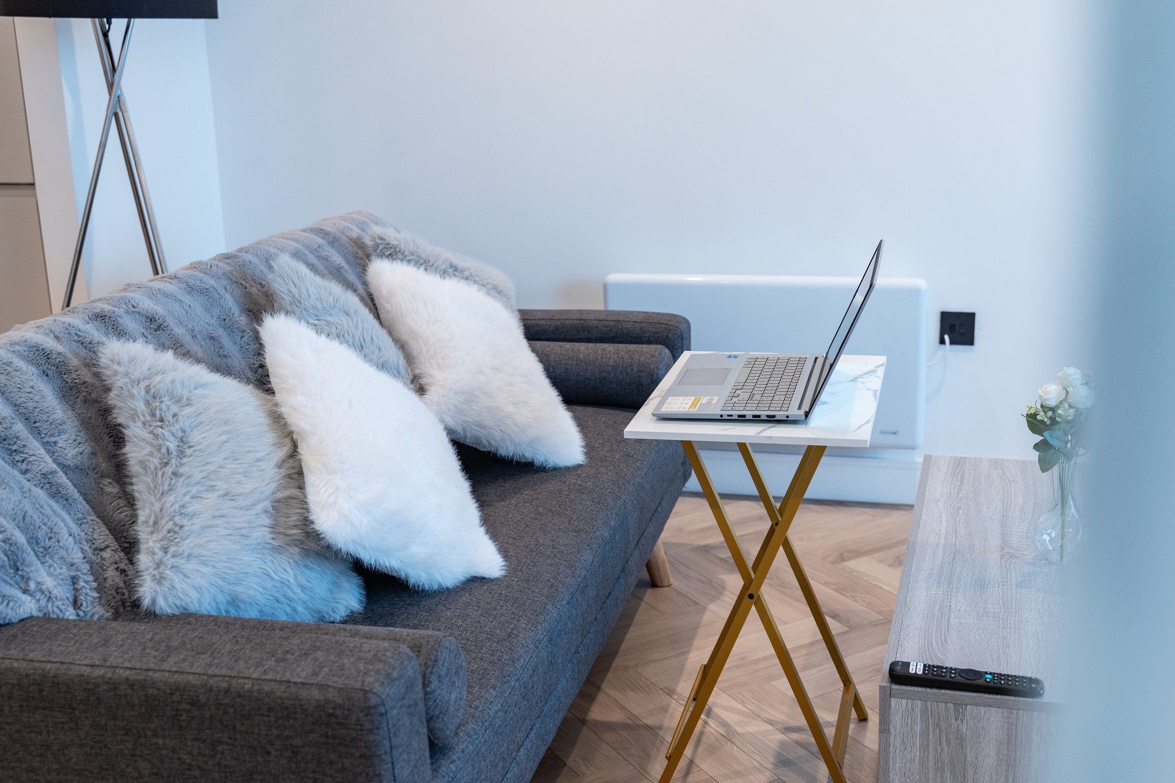 Laptop on a small desk beside the sofa