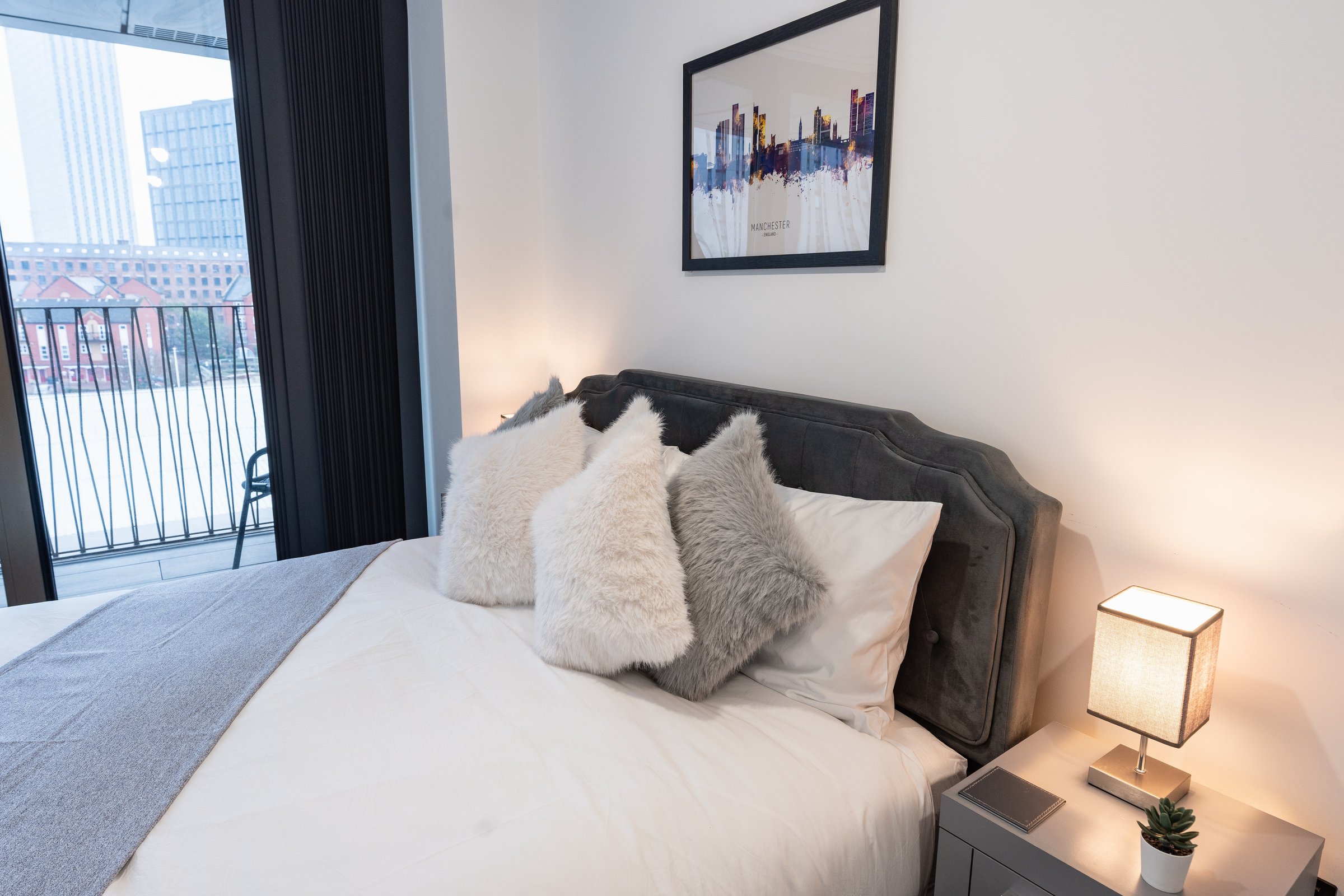 King-size bed with cushions next to the bedroom window