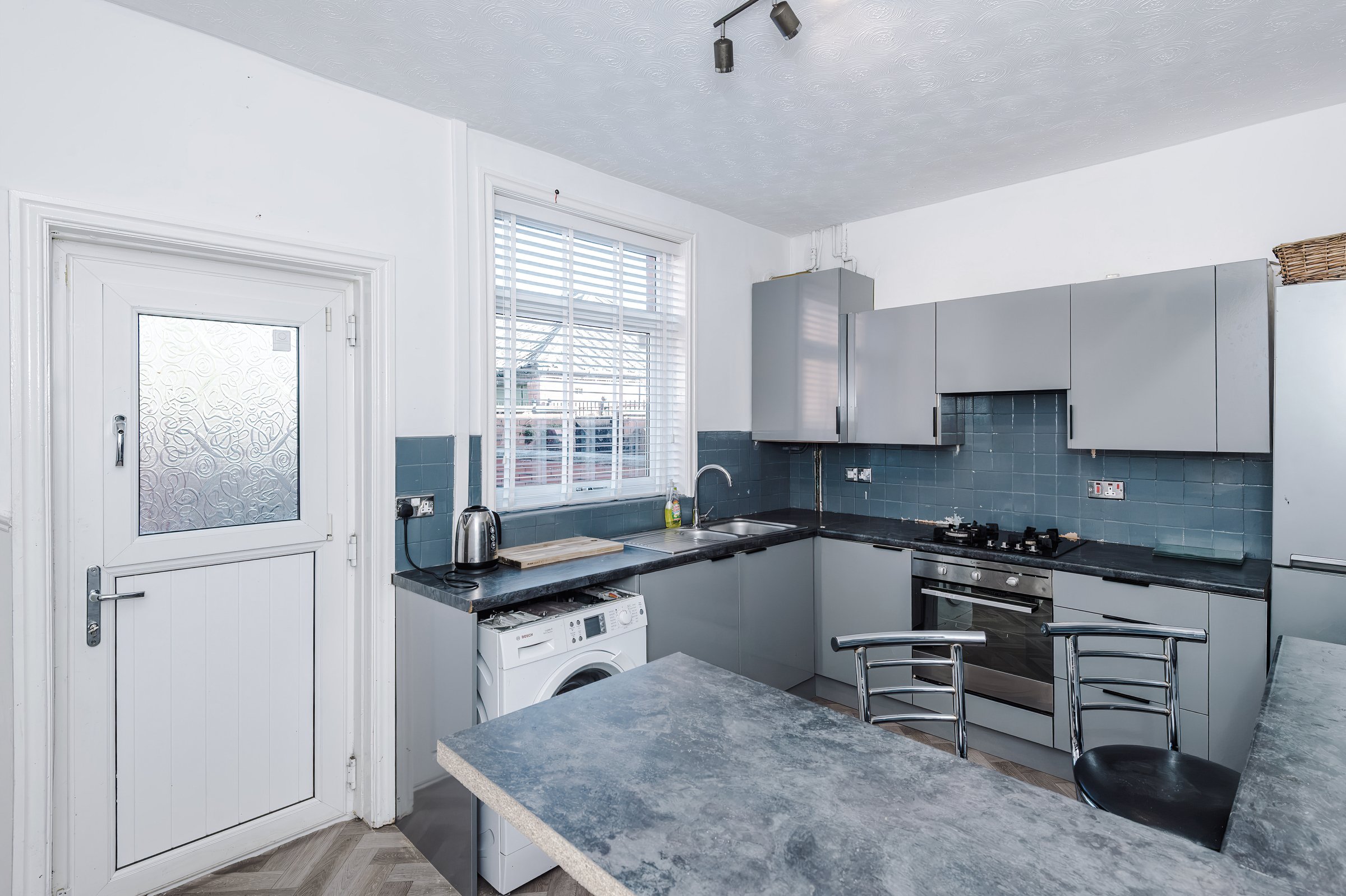 Kitchen with grey units, a dark worktop and a back door
