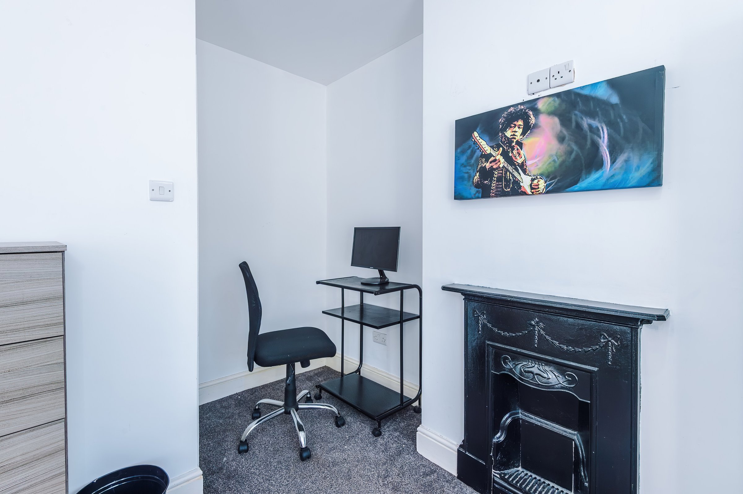 Desk, chair and computer monitor beside a black fireplace in the bedroom