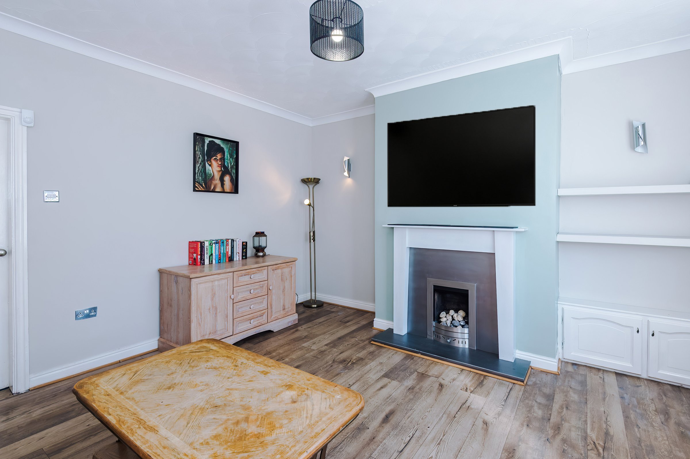 Living room with a TV above the fireplace and a wooden sideboard