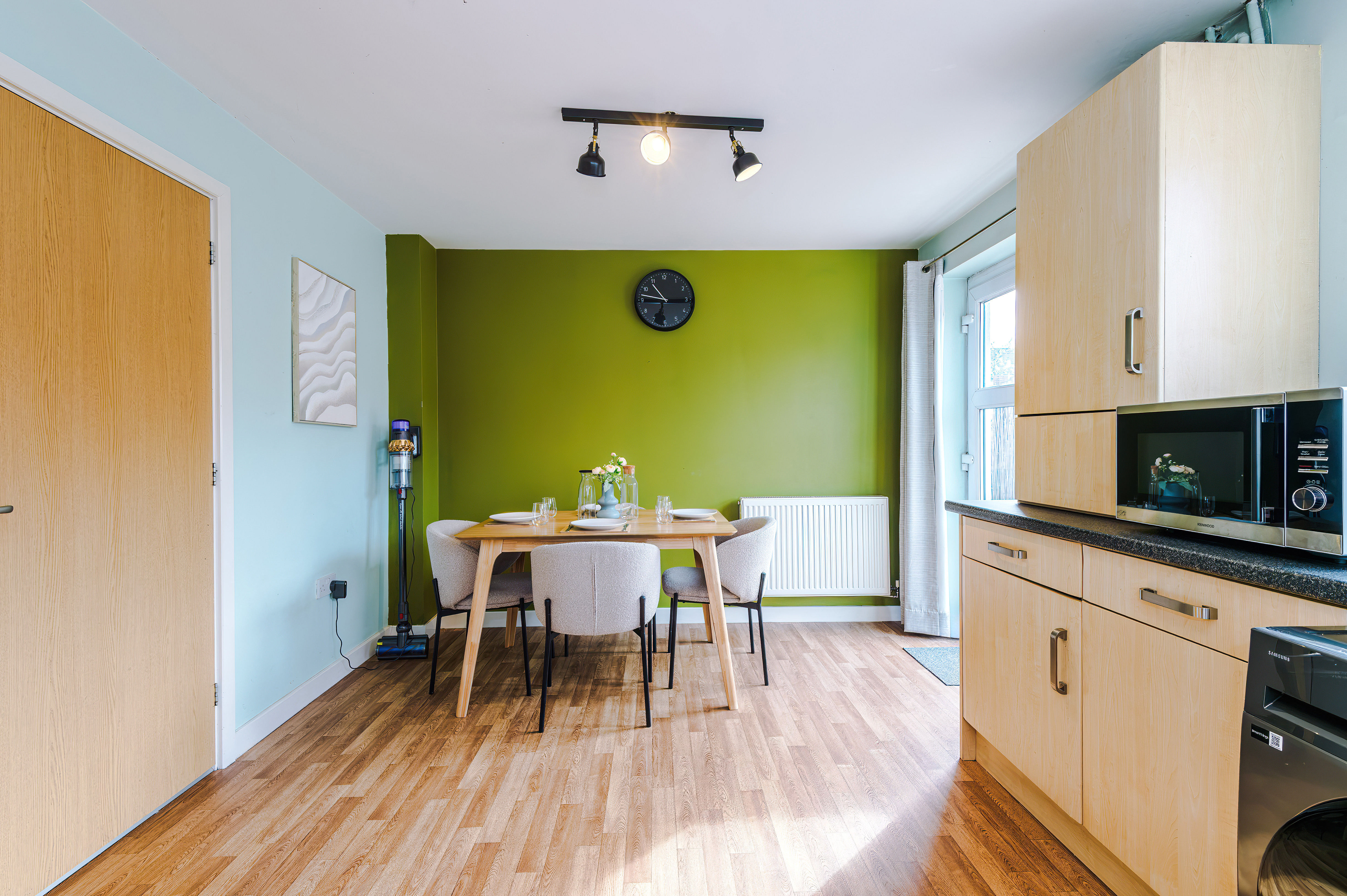 Dining area with a green feature wall, next to the kitchen