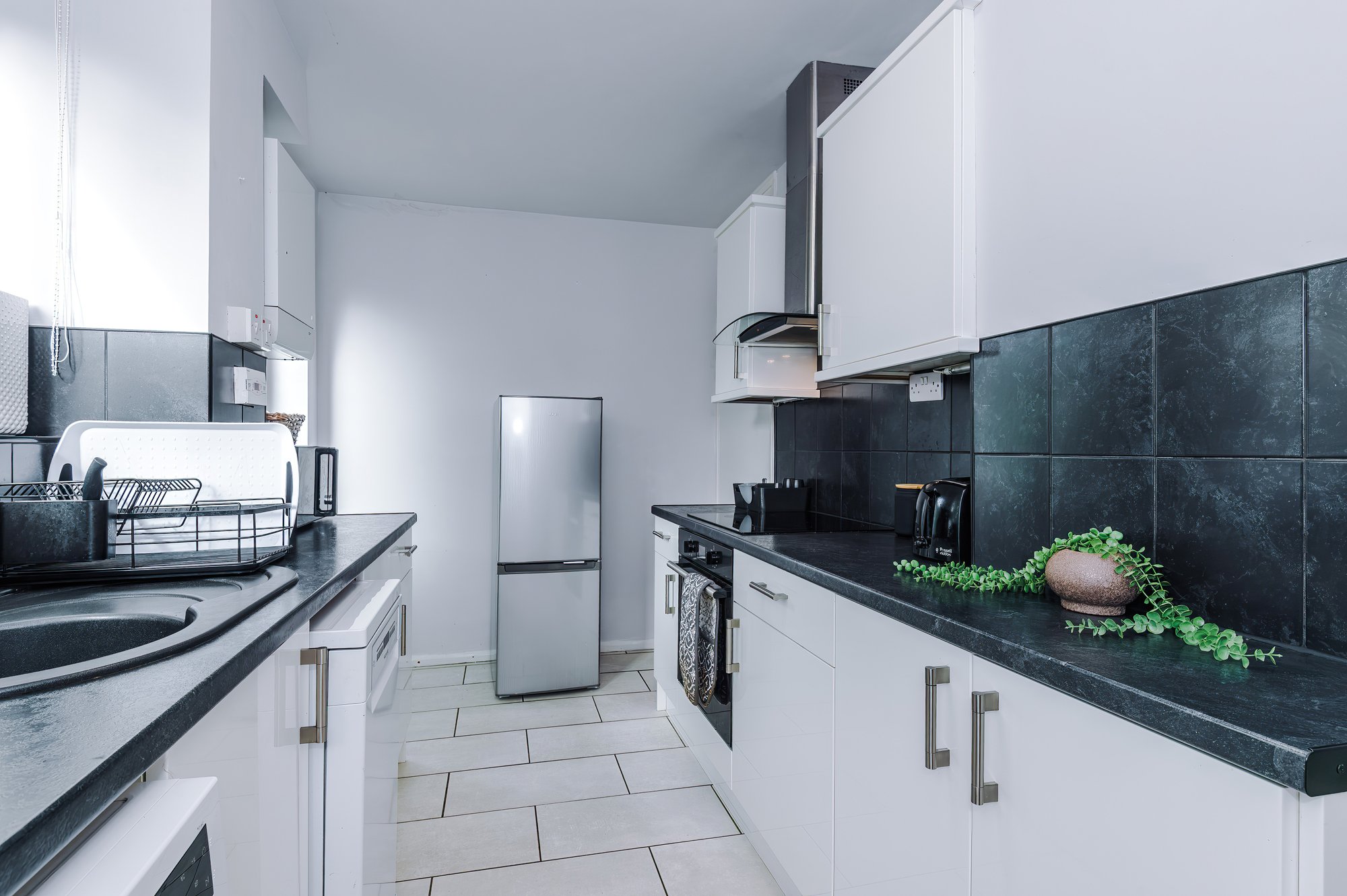 Galley kitchen with fridge freezer and tiled floor