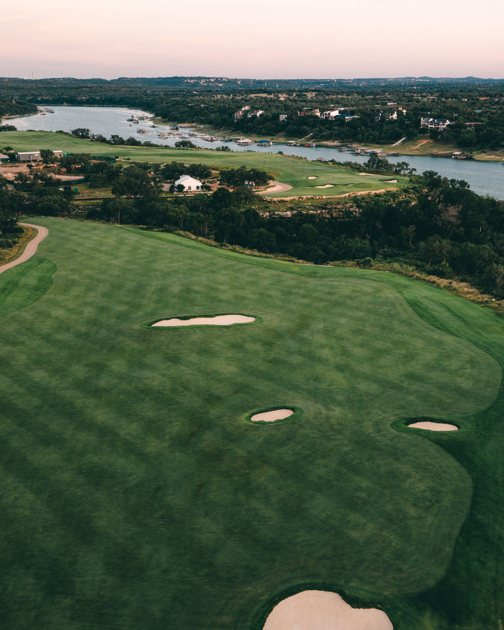 Aerial view of a golf course winding through a rugged, misty landscape.